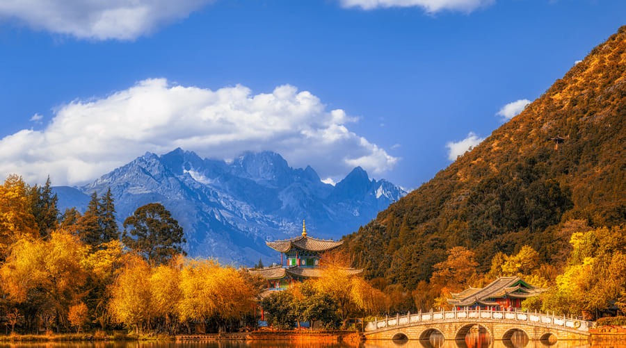 El Estanque del Dragón Negro con el Puente de los Cinco Arcos reflejado en el agua y la Montaña Nevada del Dragón de Jade al fondo en Lijiang, Yunnan, China.